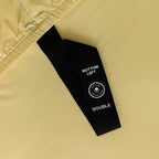 Close-up of a yellow fitted sheet with labelled corner loop strap in focus.