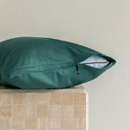 Green pillow on a textured surface with a neutral background.