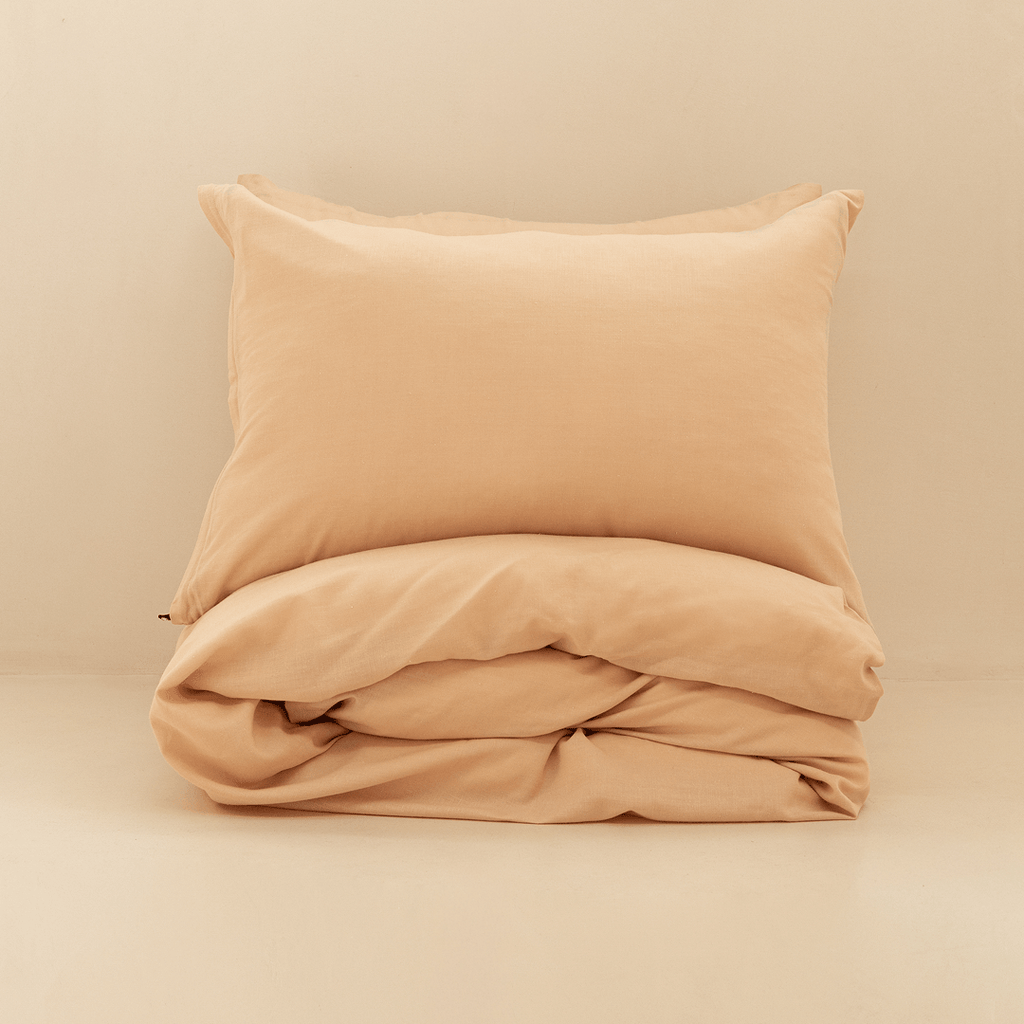 Neatly folded peach quilt cover with one matching pillowcase resting on top