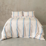 Striped duvet cover set on a bed against a concrete wall.