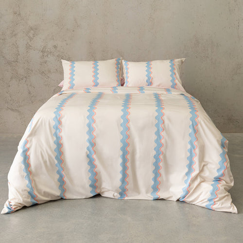 Striped duvet cover set on a bed against a concrete wall.