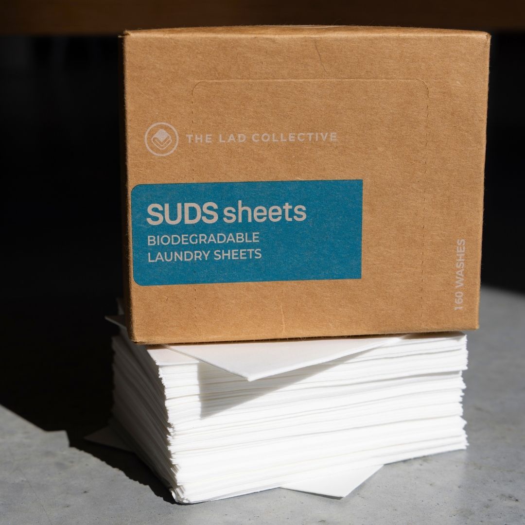 Box of SUDS sheets with biodegradable laundry sheets on a dark surface.
