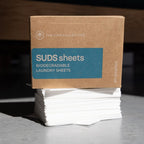 Box of SUDS sheets biodegradable laundry sheets with a brown cardboard box on a gray surface.