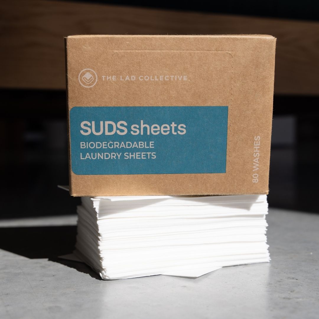 Box of SUDS sheets biodegradable laundry sheets with a brown cardboard box on a gray surface.