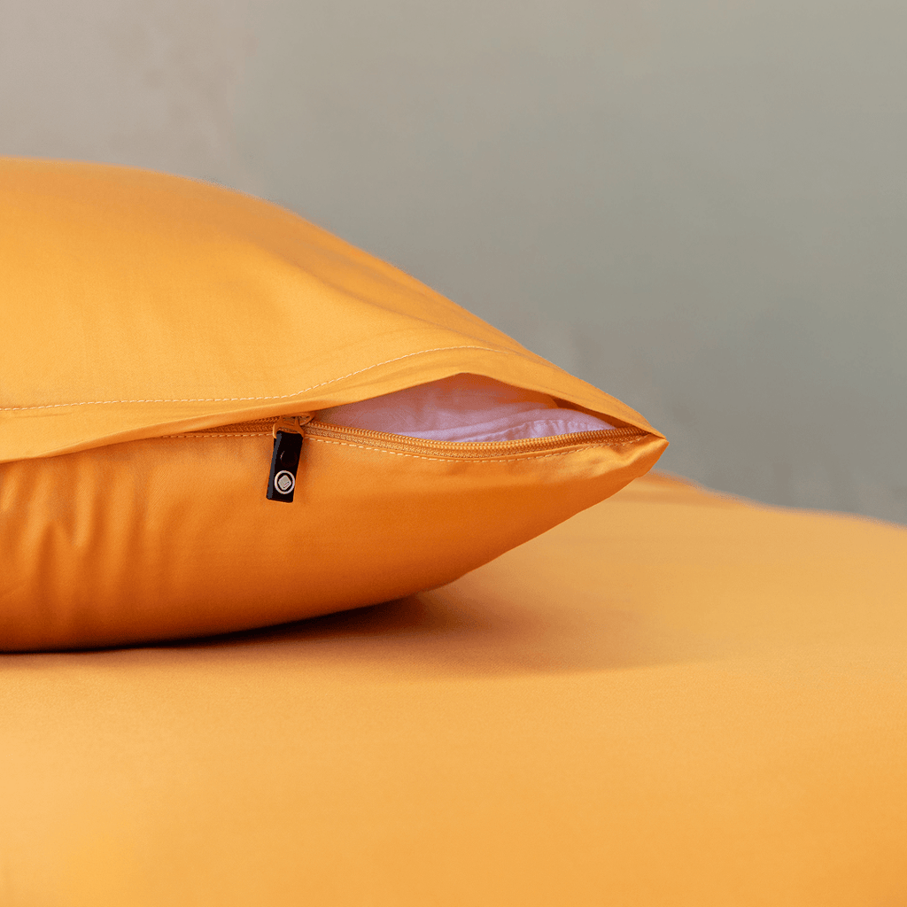 Close-up of a mustard yellow pillowcase showing a partially open zipper closure revealing white pillow fill