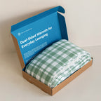 Green and white checkered blanket in a blue and brown box with text on a beige background.