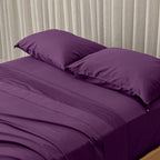 Deep purple bedding set on bed, in a neutral room. 
