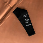 Close-up of a brown fabric with a black label on a matching brown background.
