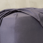 Close-up of a charcoal grey fitted sheet corner, highlighting the elasticized edge designed for a secure and snug mattress fit.