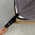 Charcoal grey fitted sheet with an orientation tag extended from the mattress corner, demonstrating the easy-to-identify labeling system for quick bed setup.