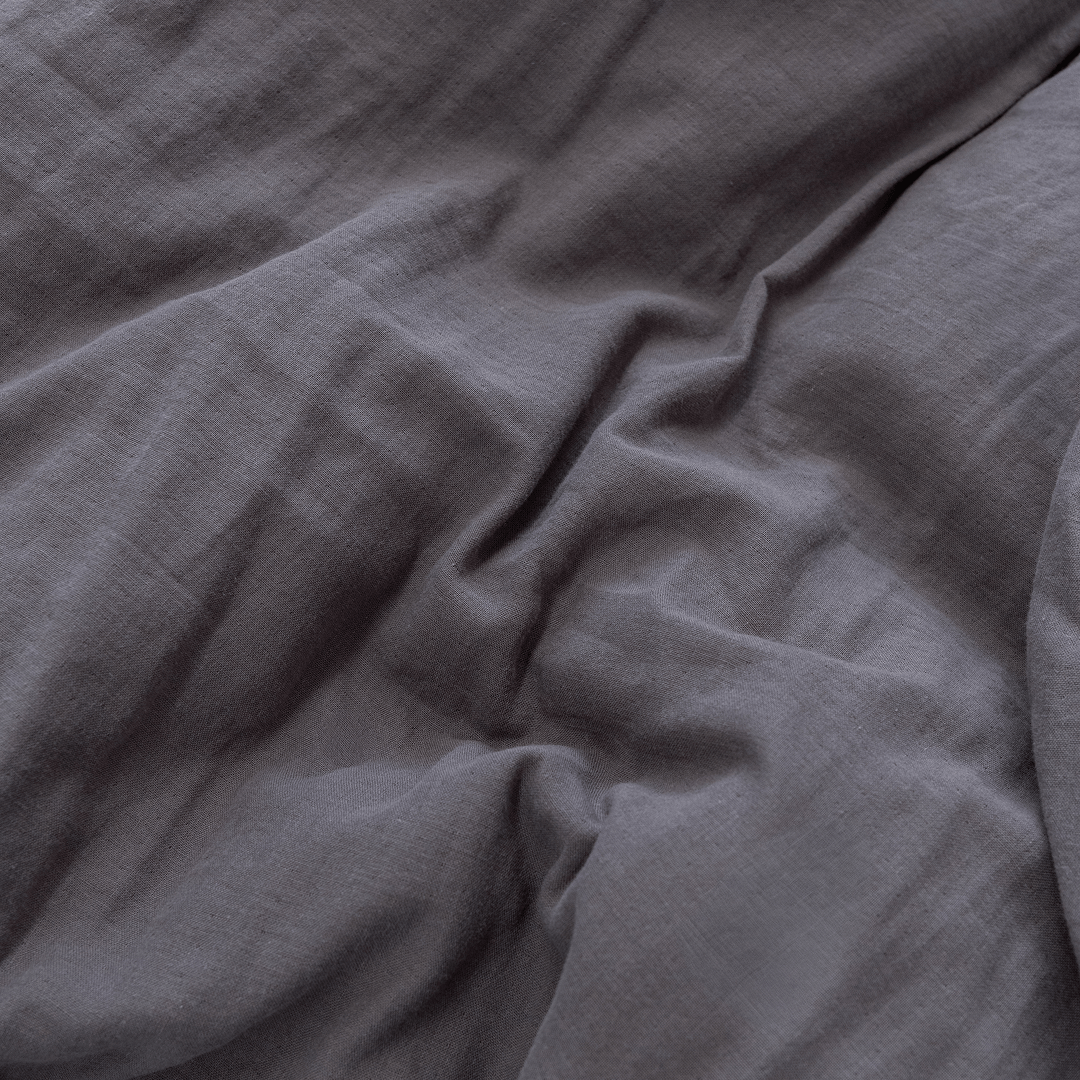 Detailed close-up of dark stone gray stonewashed fabric arranged in natural folds, highlighting its textured finish.