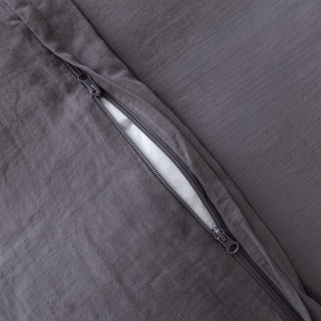 Close-up of a concealed zipper opening on a dark stone gray quilt cover with matching zipper hardware.