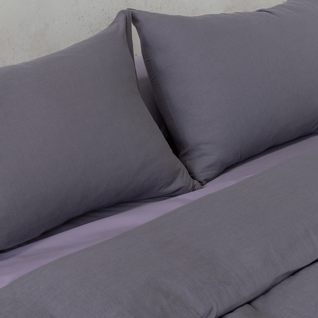 Close-up of two dark stone gray pillows resting against coordinating gray bedding.