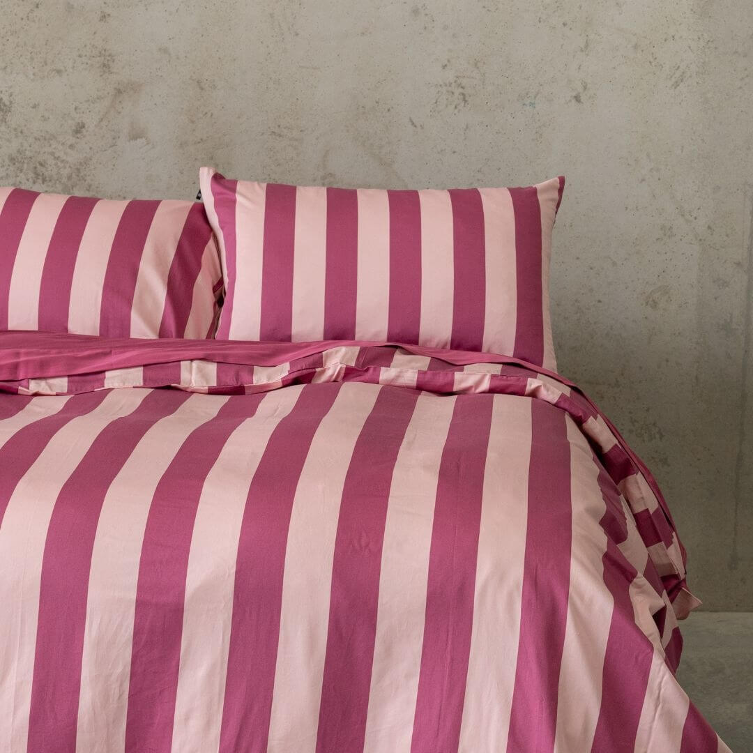Close up of raspberry pink stripe quilt cover set and pillowcases on bed.