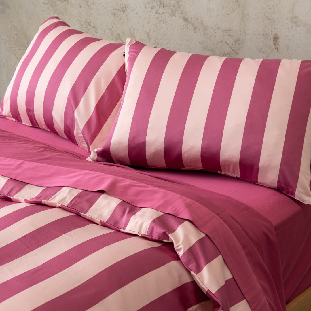 Close up of raspberry pink stripe pillowcases on bed.