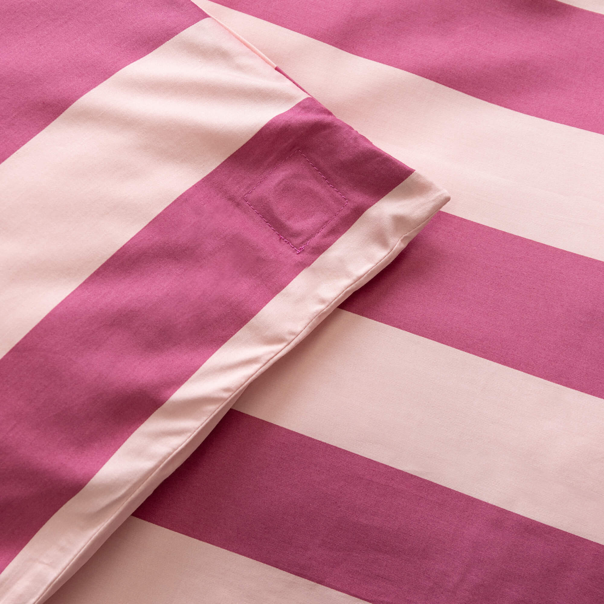 Close up of raspberry pink stripe quilt cover magnetic corner. 