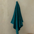 Teal towel hanging on a beige wall.
