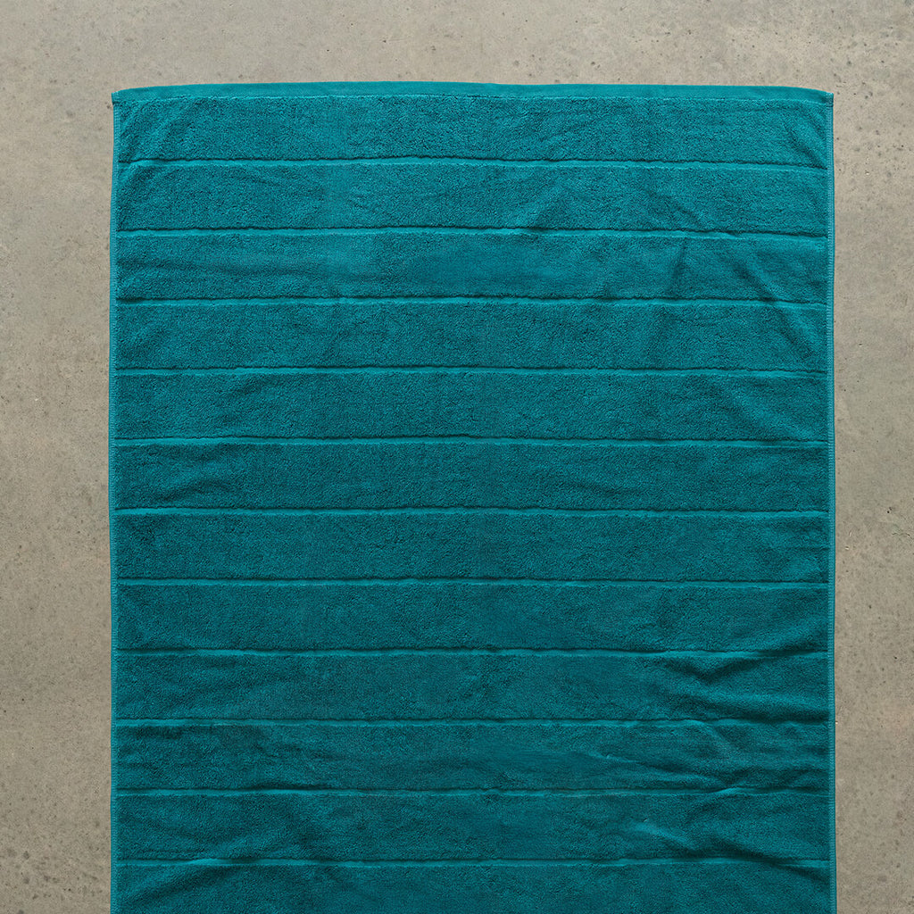 Teal bath towel laid flat.