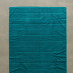 Teal bath towel laid flat.