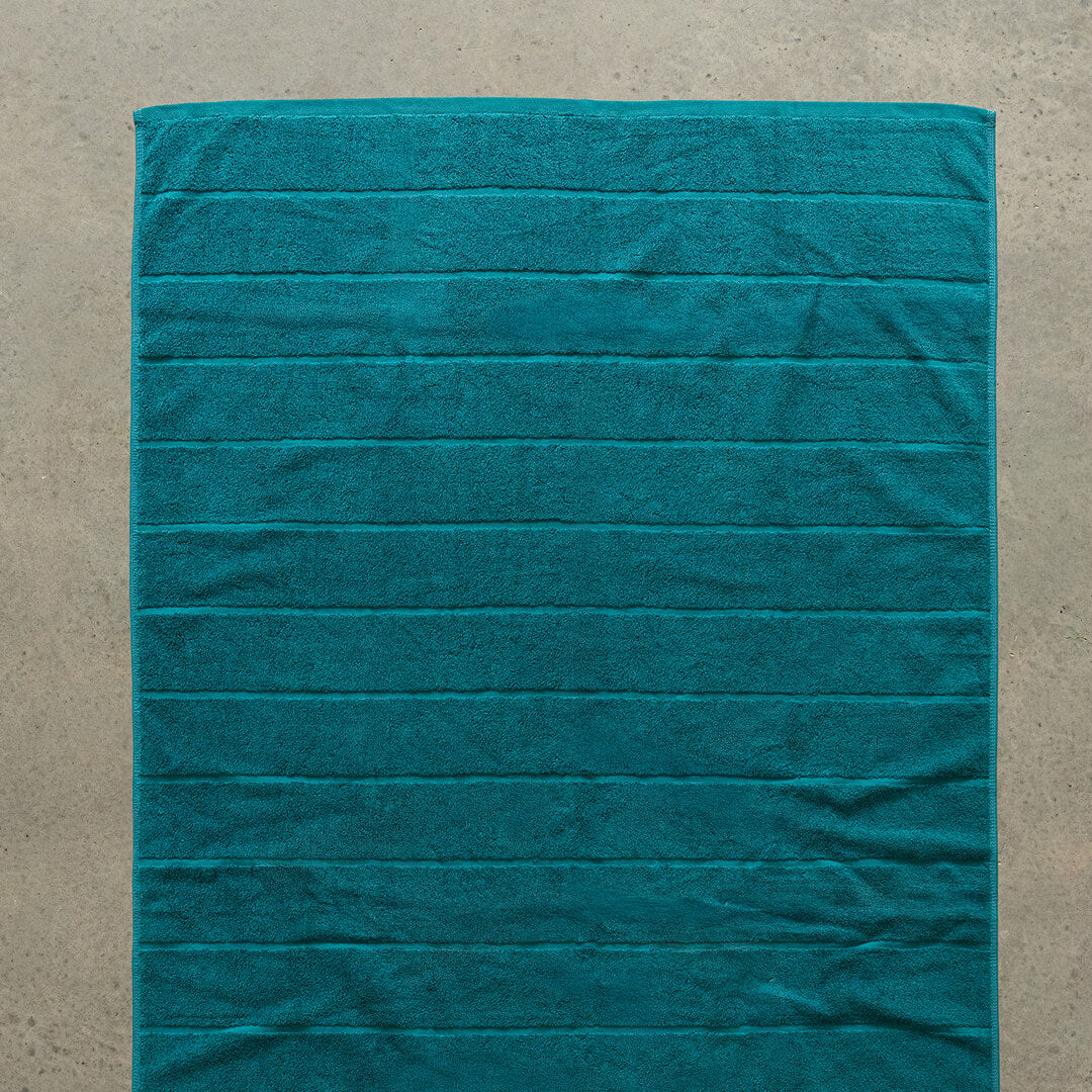 Teal bath towel laid flat.