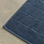Close-up of a blue bath towel on a beige floor.
