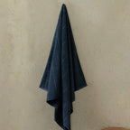 Blue towel hanging on a beige wall.