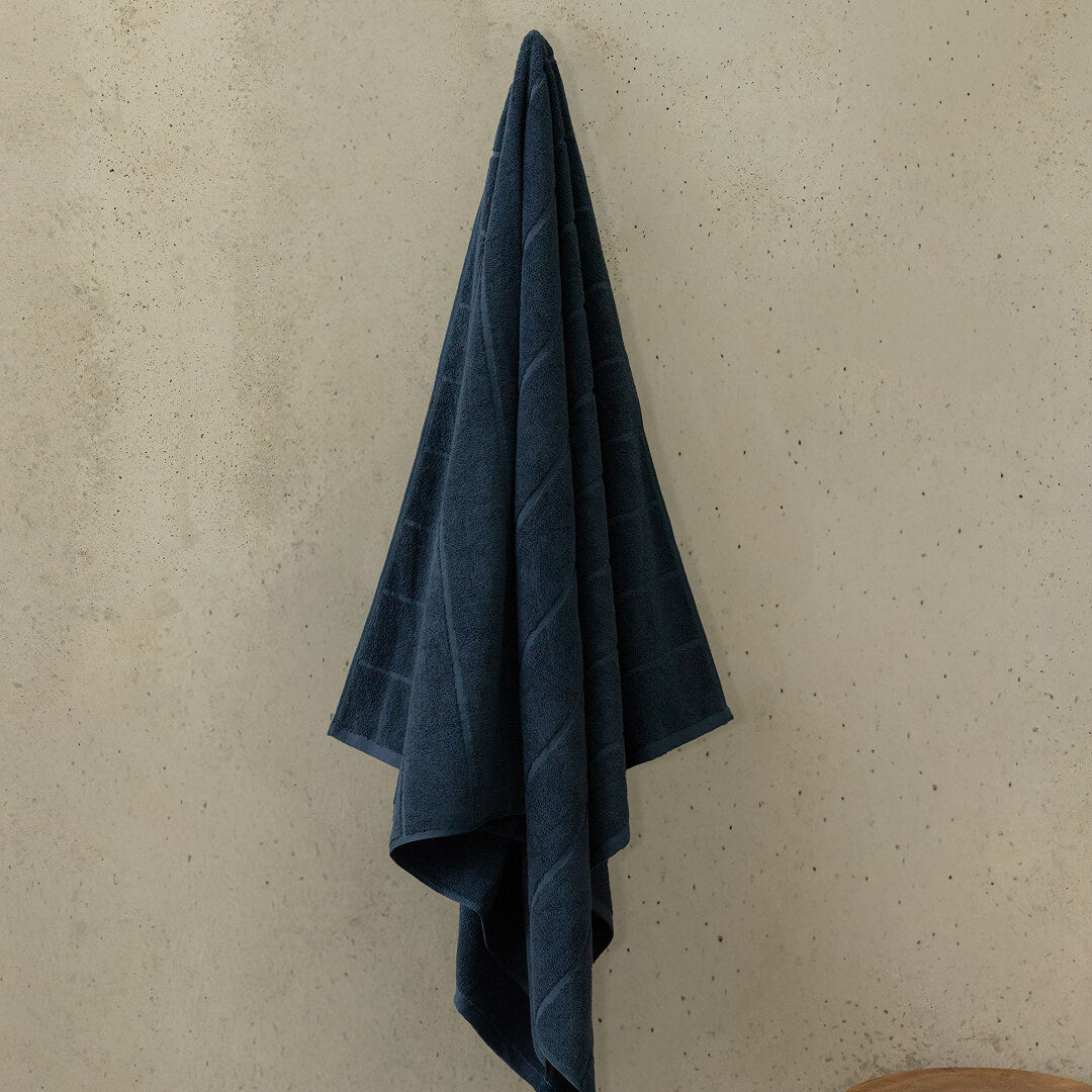 Blue towel hanging on a beige wall.
