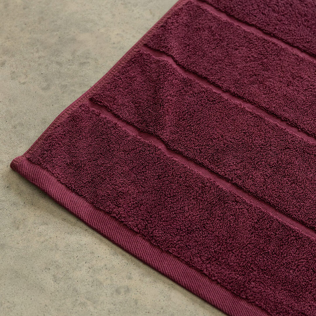 Close-up of a burgundy bath towel on  concrete.