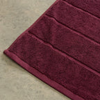 Close-up of a burgundy bath towel on  concrete.