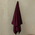 Maroon towel hanging on a beige wall