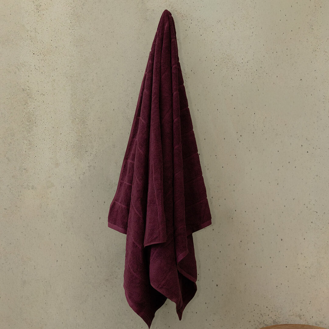 Maroon towel hanging on a beige wall