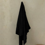 Black towel hanging on a hook against a beige wall.