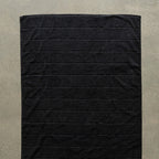 Black bath towel laid flat on a concrete floor.
