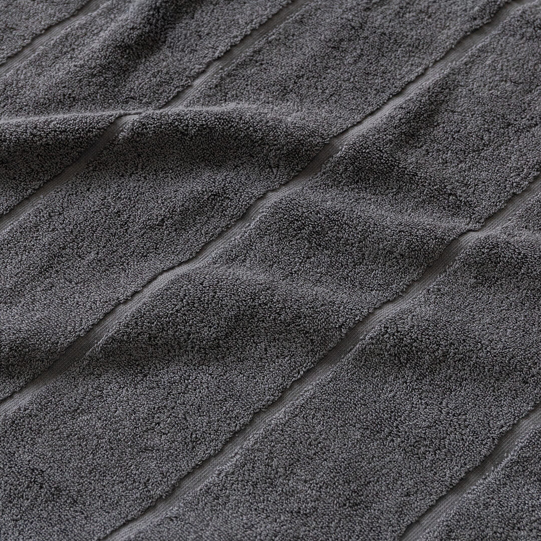 Close-up of textured charcoal grey bath towel fabric with diagonal lines.