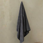 Gray towel hanging on a beige wall.