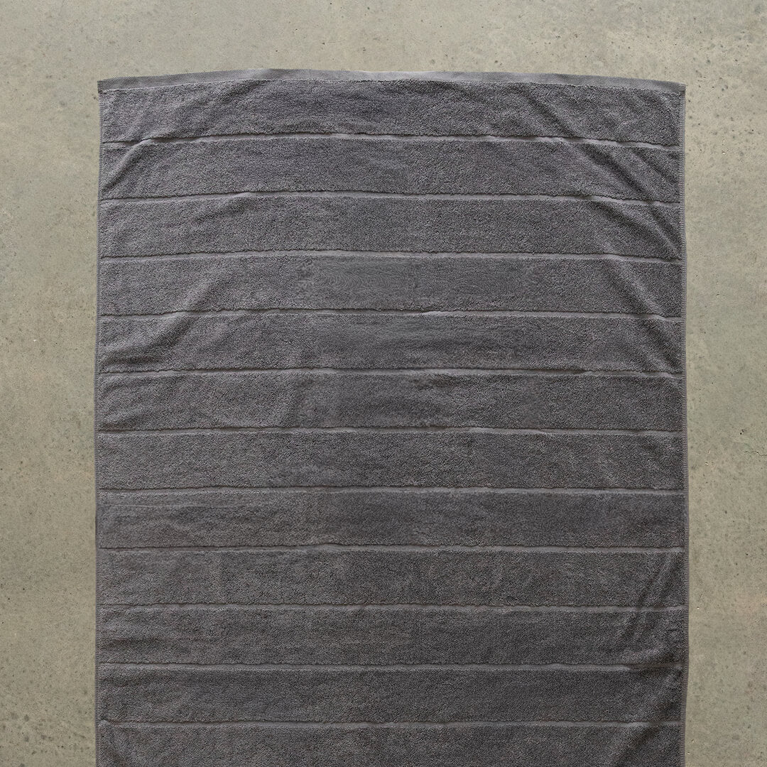 Grey textured towel laid flat on a beige background.