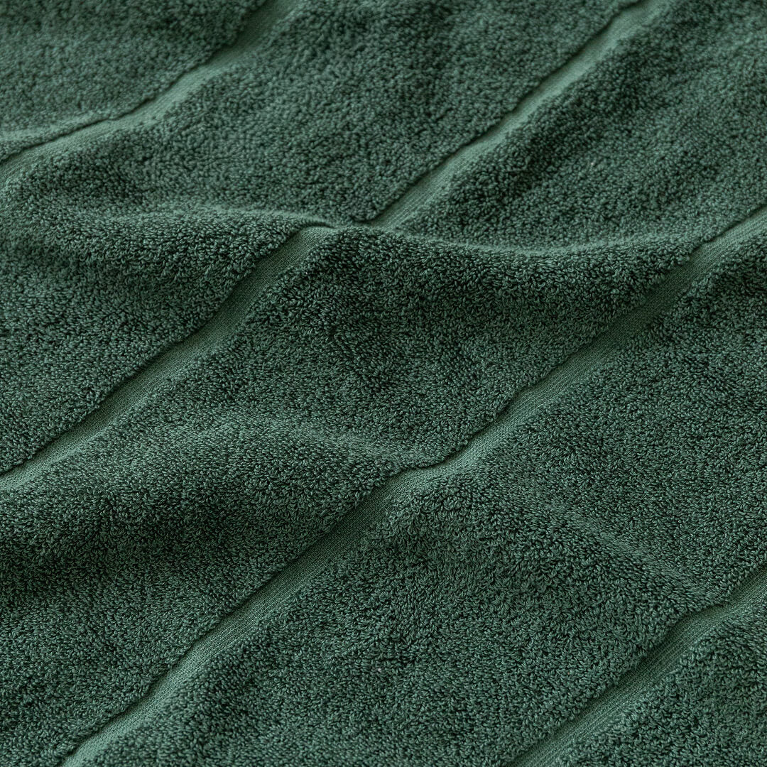 Close-up of textured green towel fabric with folds.