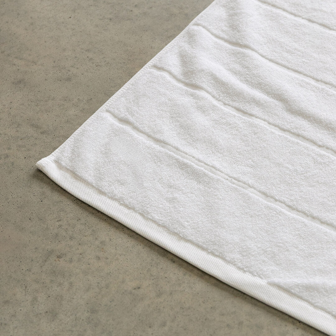 White bath towel corner contrast against concrete background.