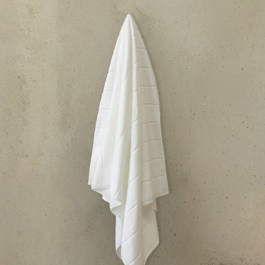 White towel hanging on a beige wall.
