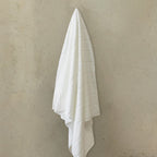 White towel hanging on a beige wall.