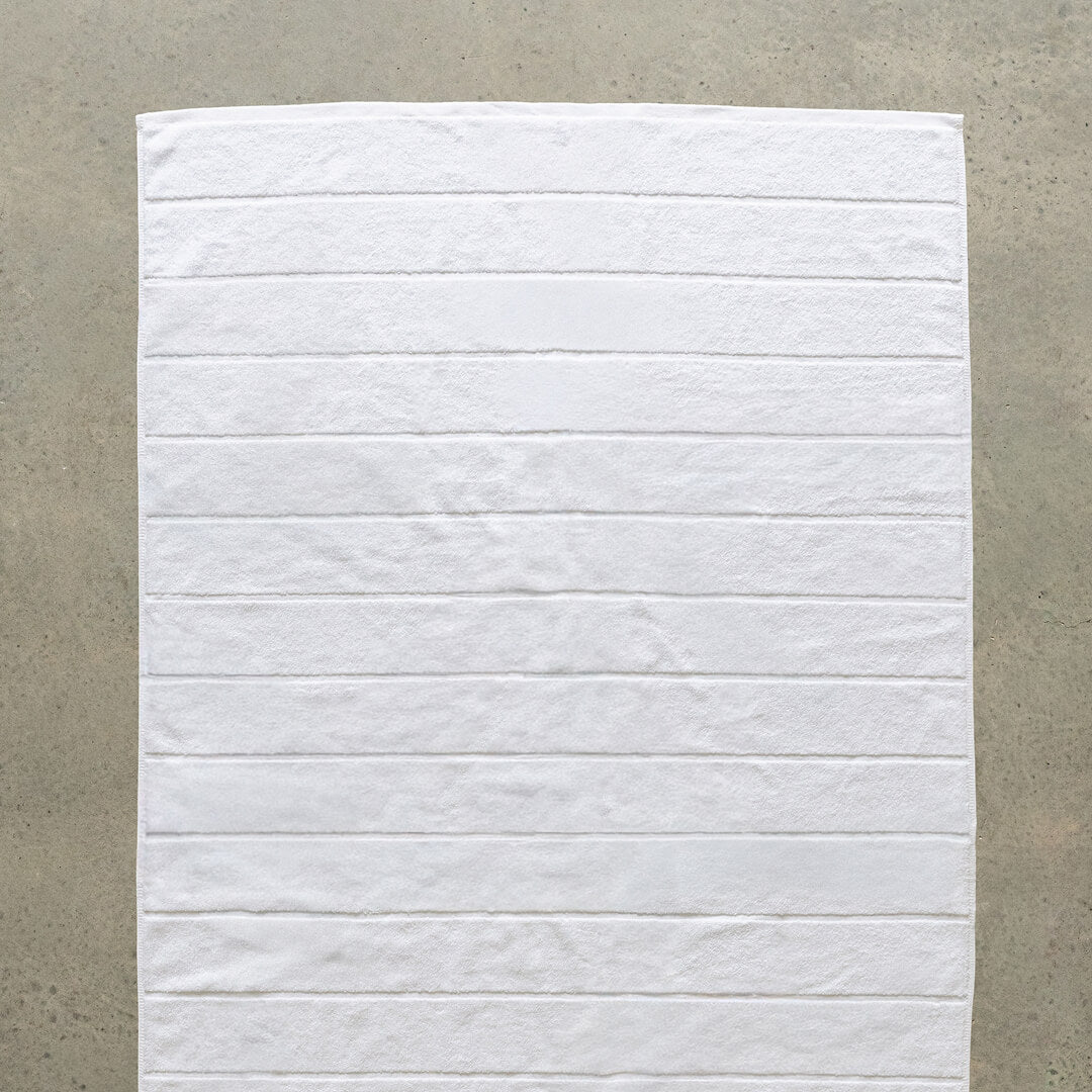 White bath towel laid flat on concrete background.