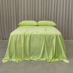 Lime green bedspread on a bed with natural curtains in the background.
