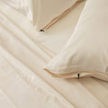 Cream bedding set with pillows on a plain background.