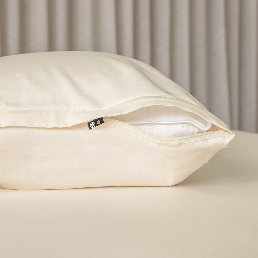 Cream invisible zip pillowcase showing the zip half open on a pillow.