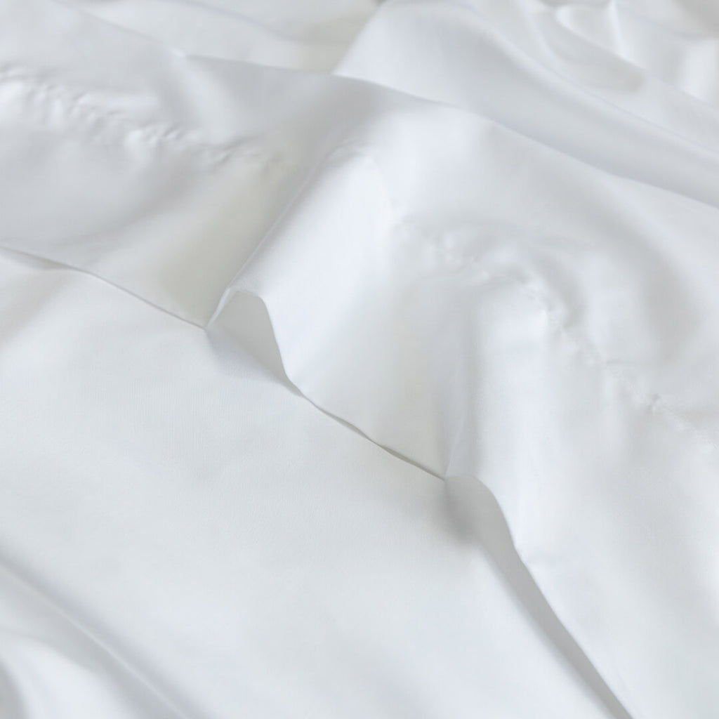 Close-up of white top sheet fabric with folds.