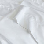 Close-up of white top sheet fabric with folds.