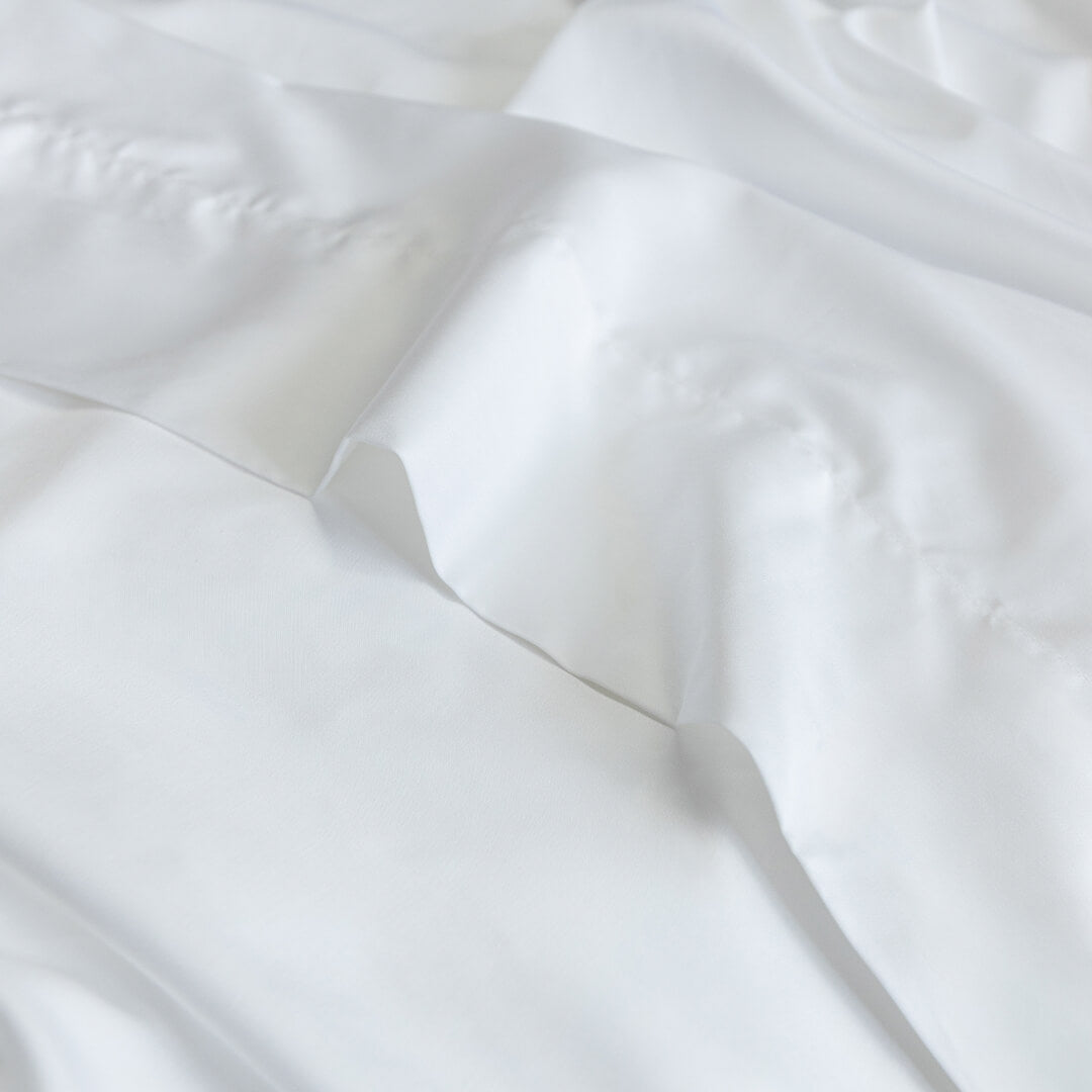 Close-up of white top sheet fabric with folds.