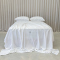 White bedspread with a brand logo on a bed against a neutral background
