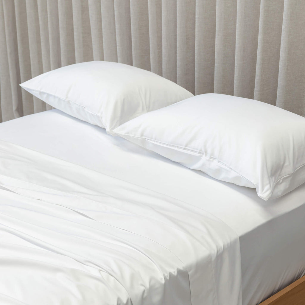 close up of white pillows and bedding on curtain background