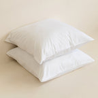 Two white Euorpean pillowcases on top of each other, with a neutral background.